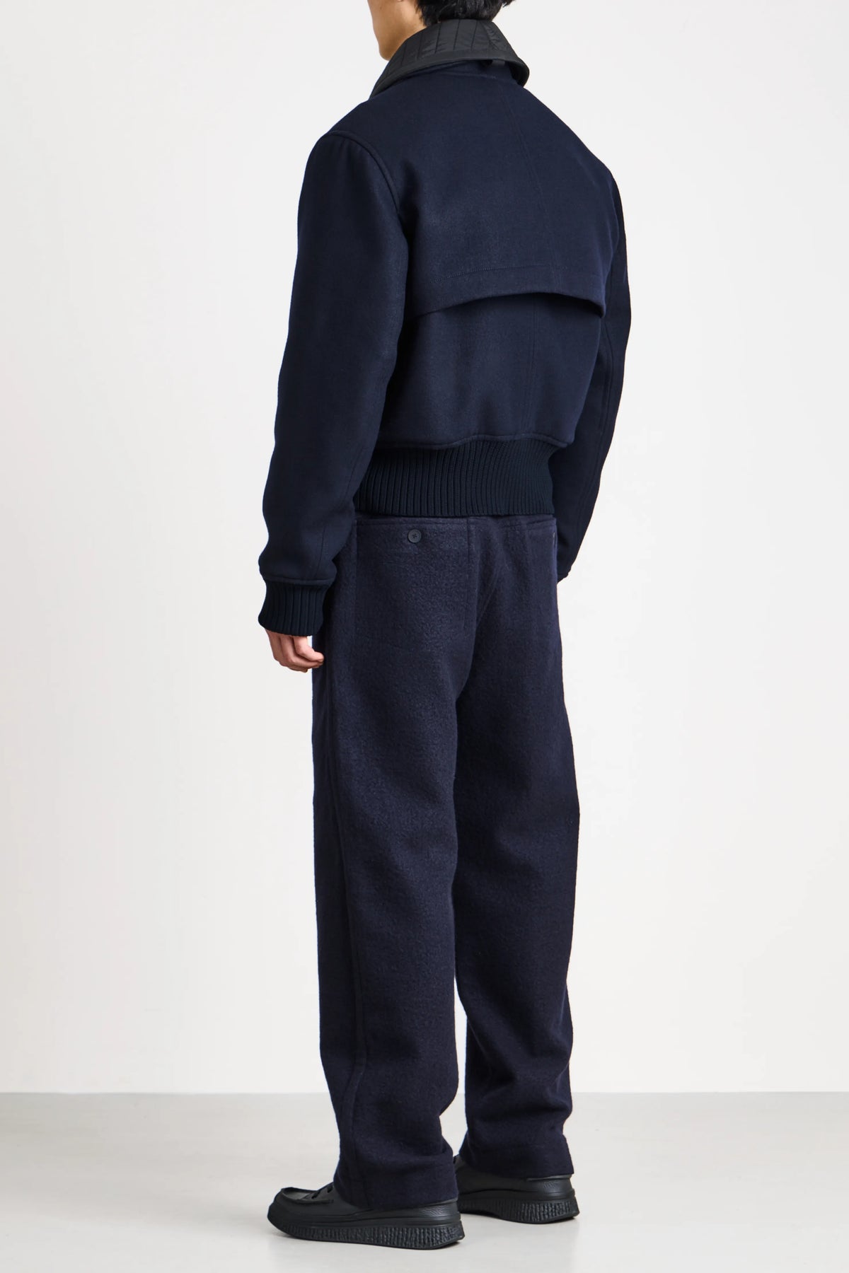 Full length back view of the navy wool flight jacket by Craig Green on a model